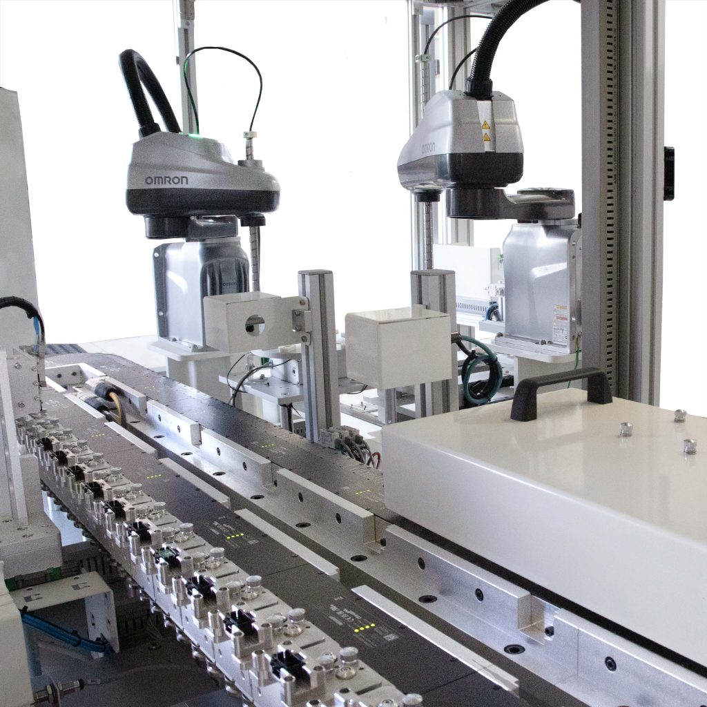 Interior view of automated station with magnetic conveyor and two pick-and-place robots